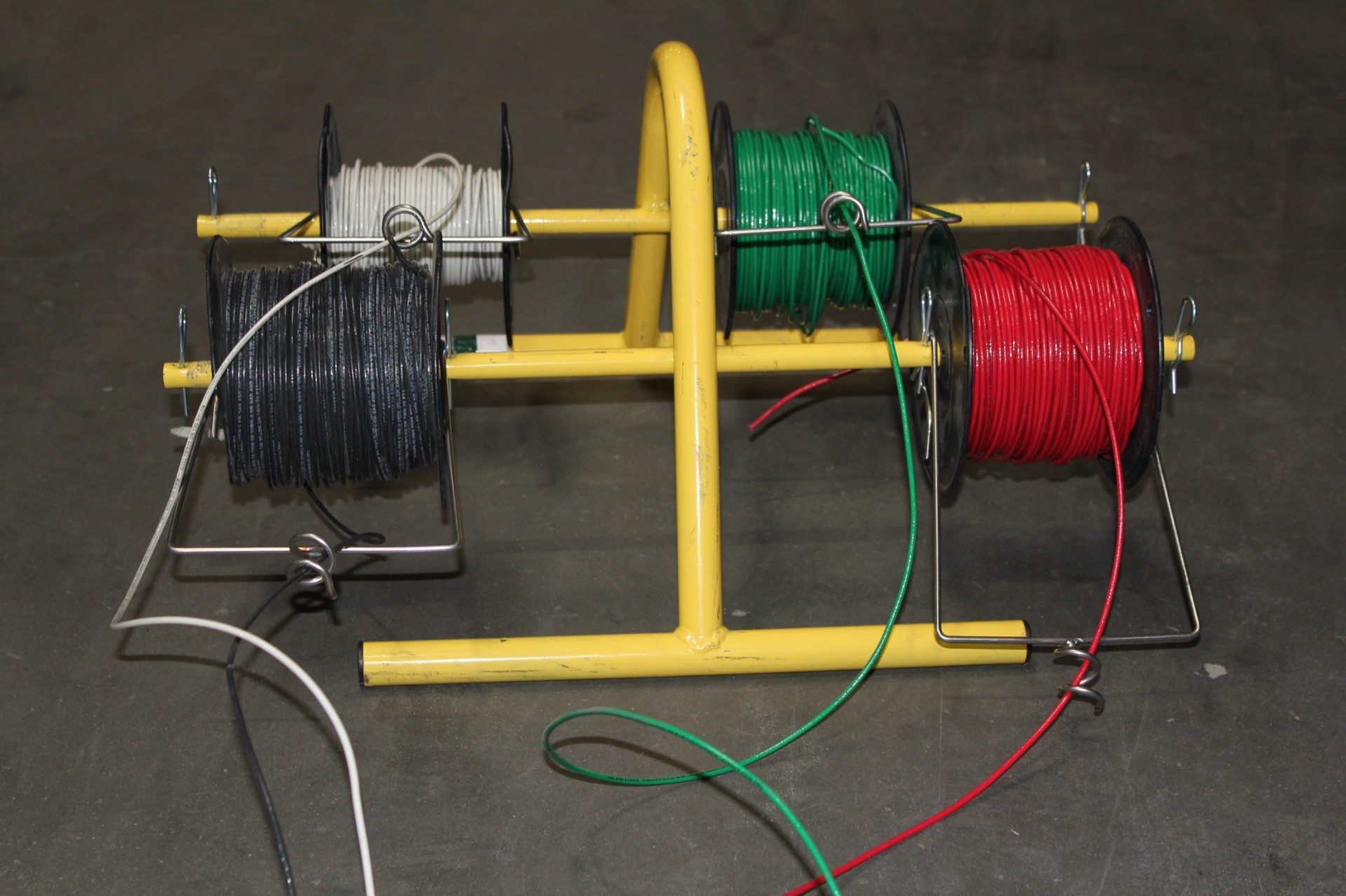 SpoolPig wire spool caddy loaded with red, green, and black electrical wire spools on a jobsite cart